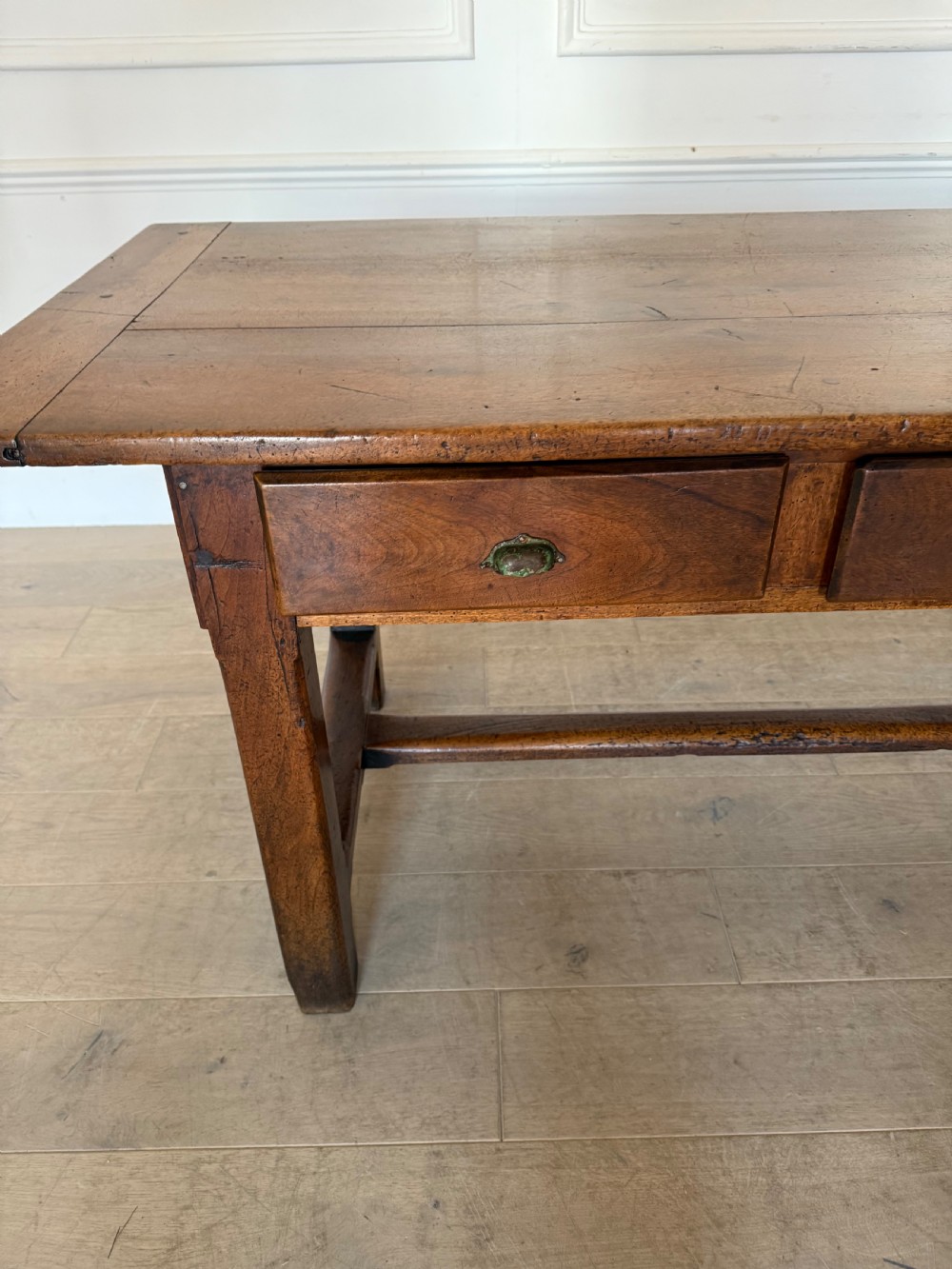 A rectangular 19th-century walnut drapers table featuring a plank top, three drawers with metal drop handles, and an H-stretcher base. View VII