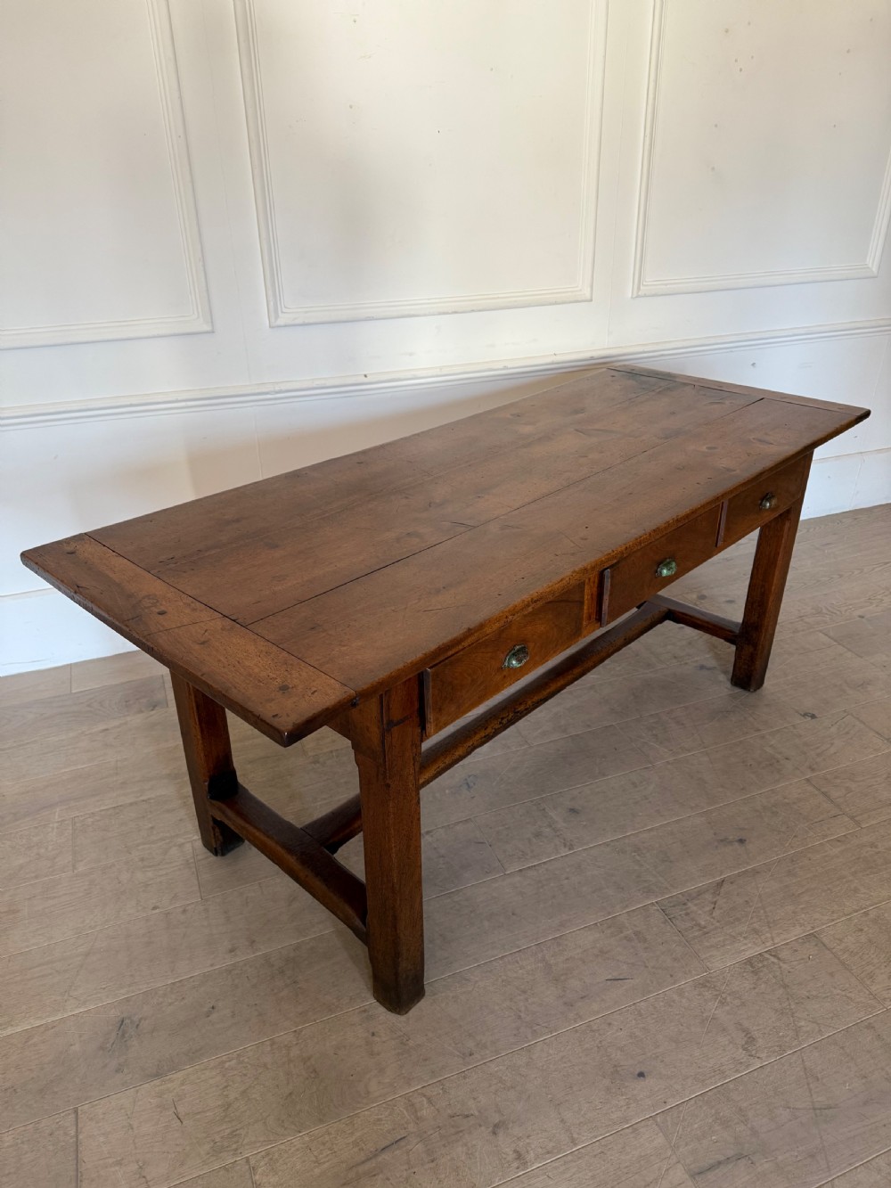 A rectangular 19th-century walnut drapers table featuring a plank top, three drawers with metal drop handles, and an H-stretcher base. View VIII