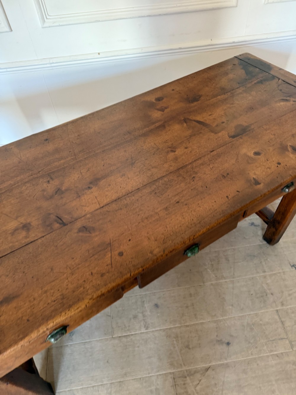 A rectangular 19th-century walnut drapers table featuring a plank top, three drawers with metal drop handles, and an H-stretcher base. View X