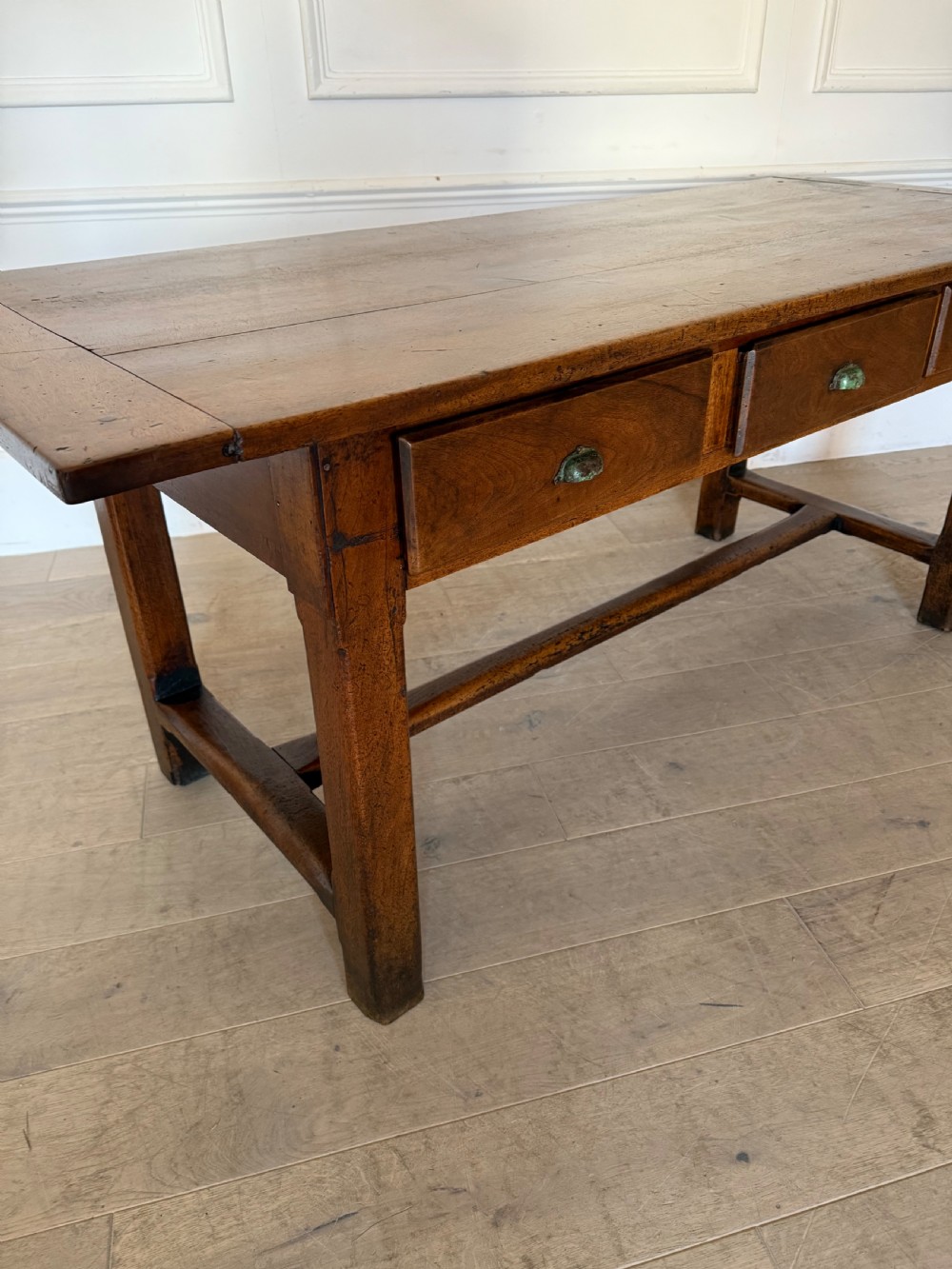 A rectangular 19th-century walnut drapers table featuring a plank top, three drawers with metal drop handles, and an H-stretcher base. View XII