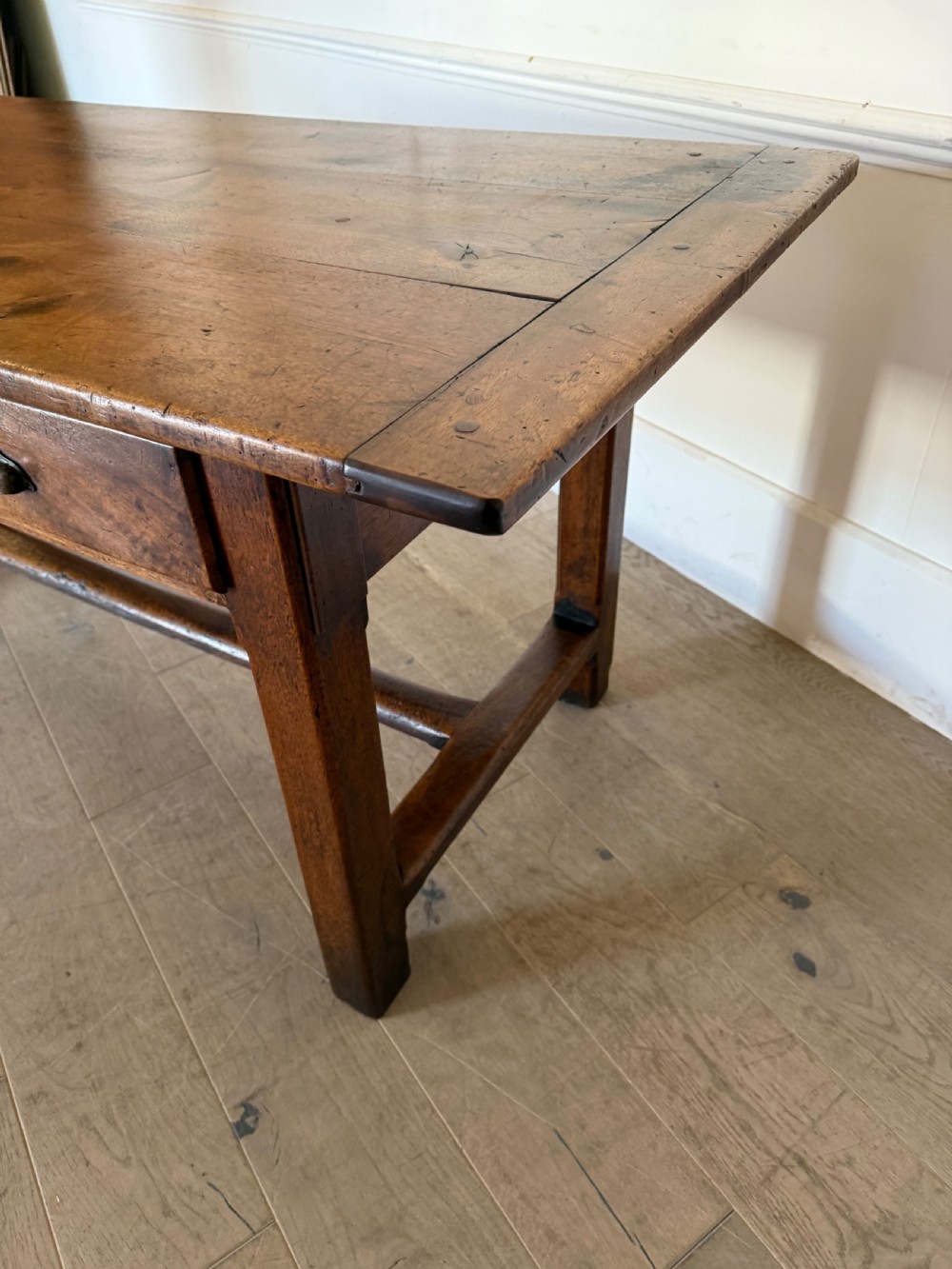 A rectangular 19th-century walnut drapers table featuring a plank top, three drawers with metal drop handles, and an H-stretcher base. View XIV