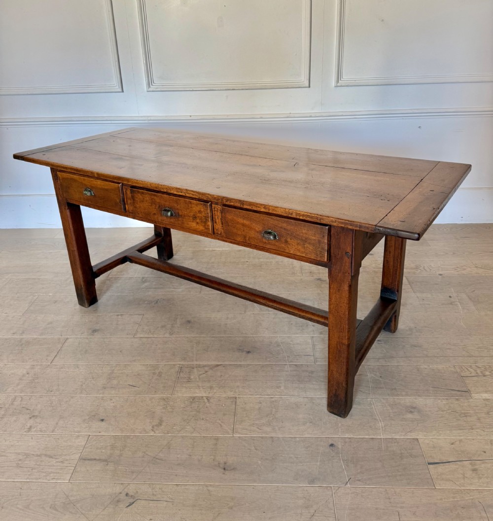 A rectangular 19th-century walnut drapers table featuring a plank top, three drawers with metal drop handles, and an H-stretcher base. View XV