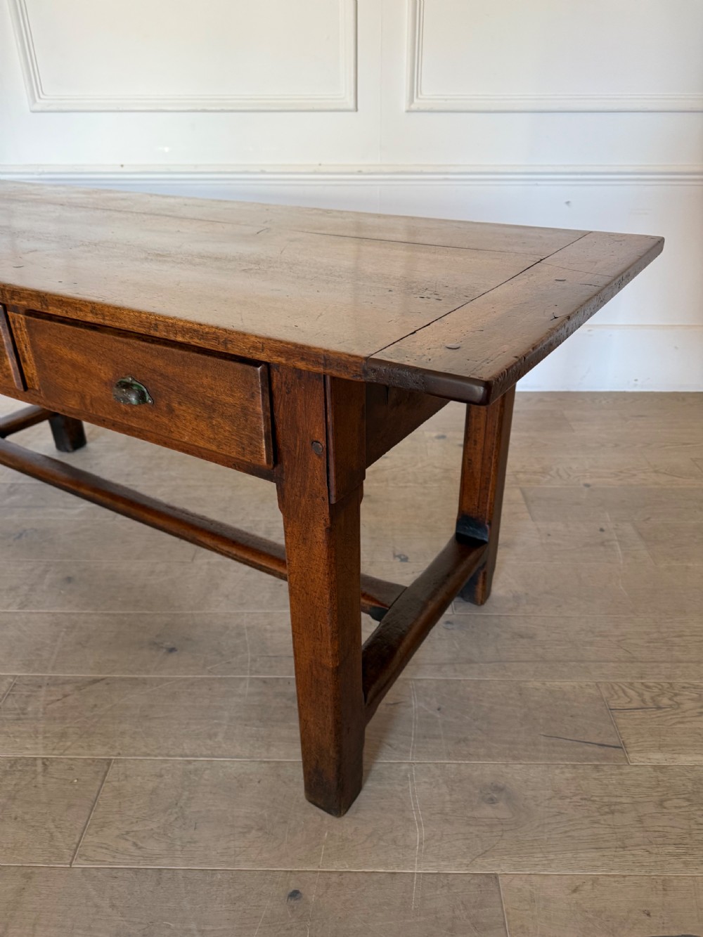 A rectangular 19th-century walnut drapers table featuring a plank top, three drawers with metal drop handles, and an H-stretcher base. View XVI