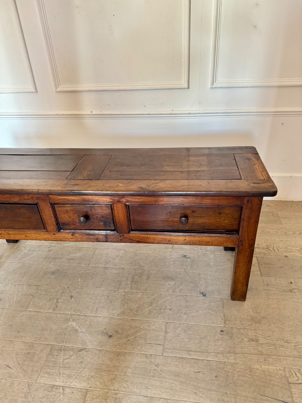 A rectangular early 19th-century chestnut dresser base featuring three drawers with turned wooden knobs and straight legs. View II