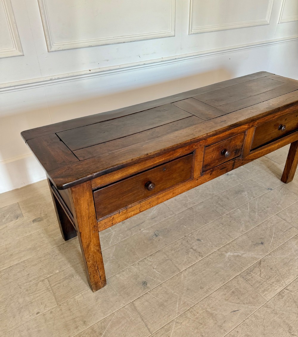 A rectangular early 19th-century chestnut dresser base featuring three drawers with turned wooden knobs and straight legs. View III