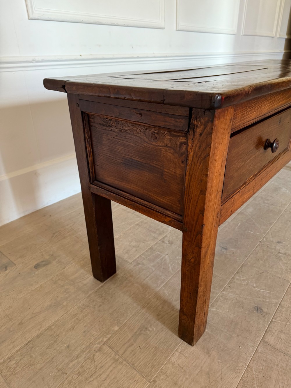 A rectangular early 19th-century chestnut dresser base featuring three drawers with turned wooden knobs and straight legs. View VII