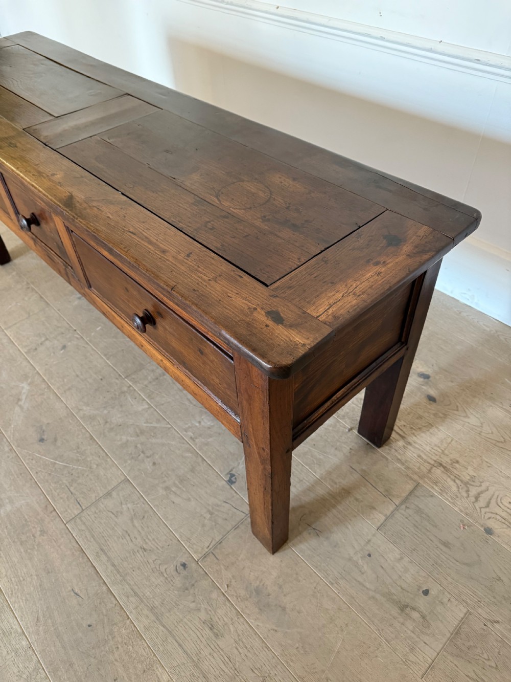 A rectangular early 19th-century chestnut dresser base featuring three drawers with turned wooden knobs and straight legs. View VIII