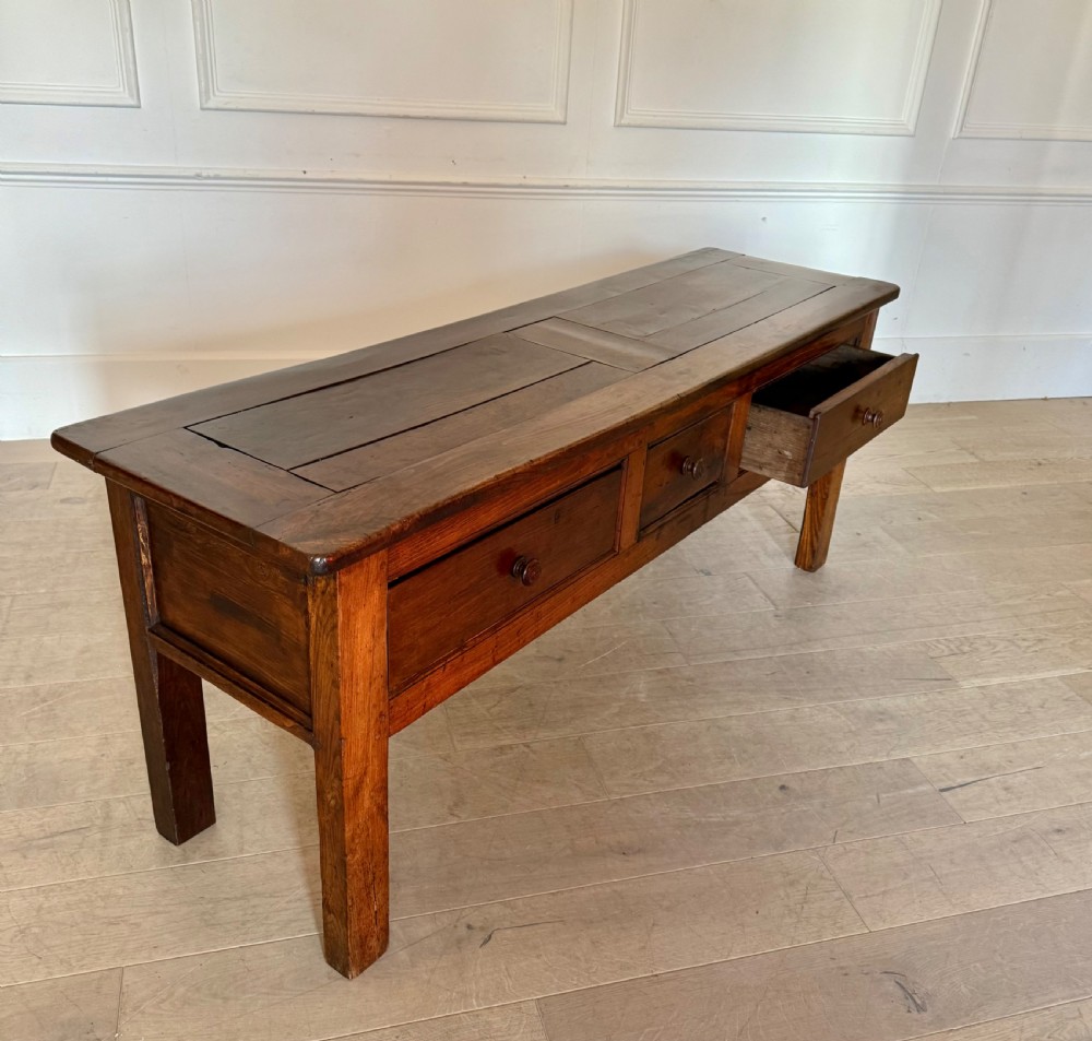 A rectangular early 19th-century chestnut dresser base featuring three drawers with turned wooden knobs and straight legs. View XI