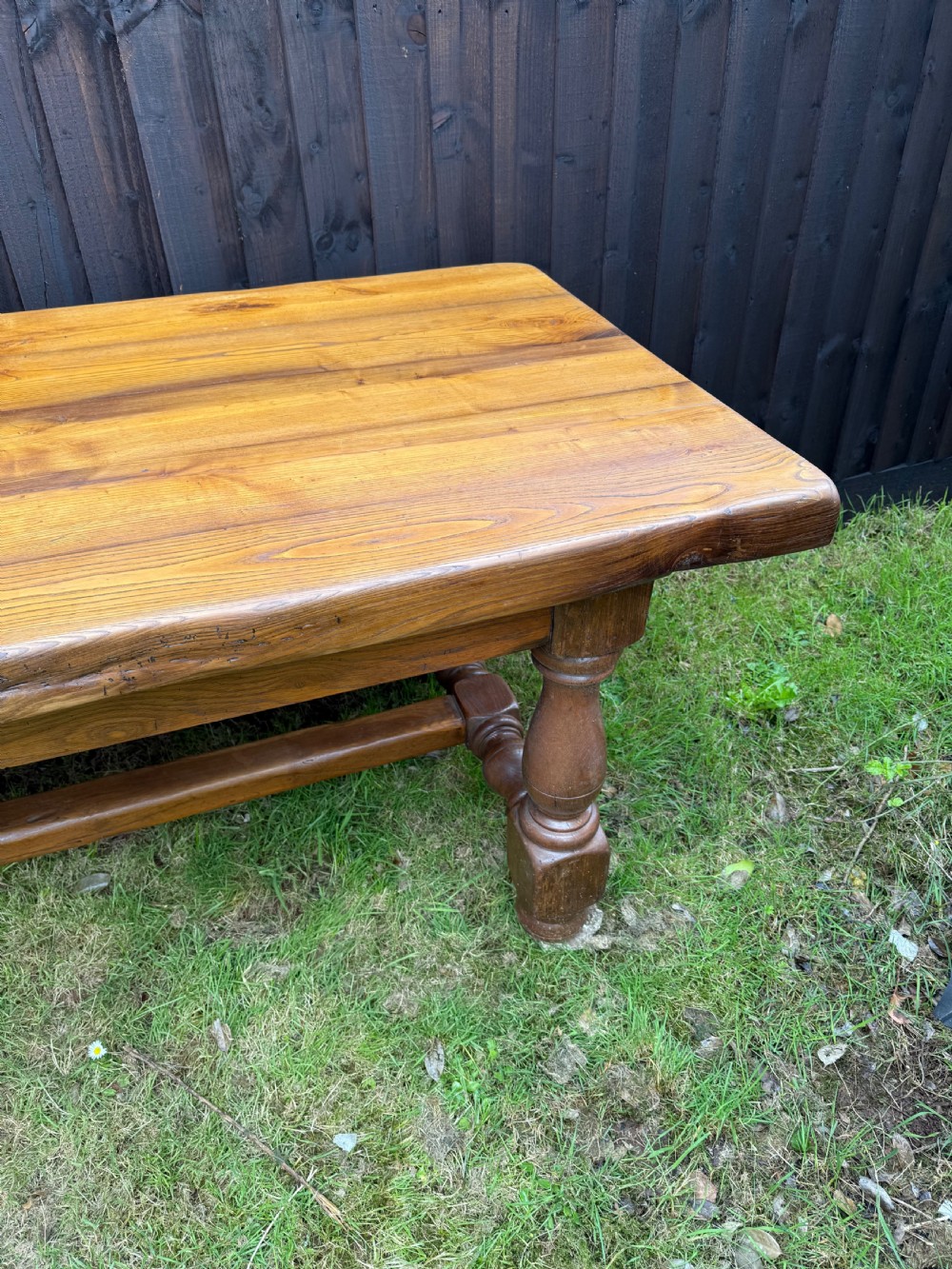 A large solid oak refectory dining table featuring a thick plank top, turned legs, and a low central stretcher base. View II