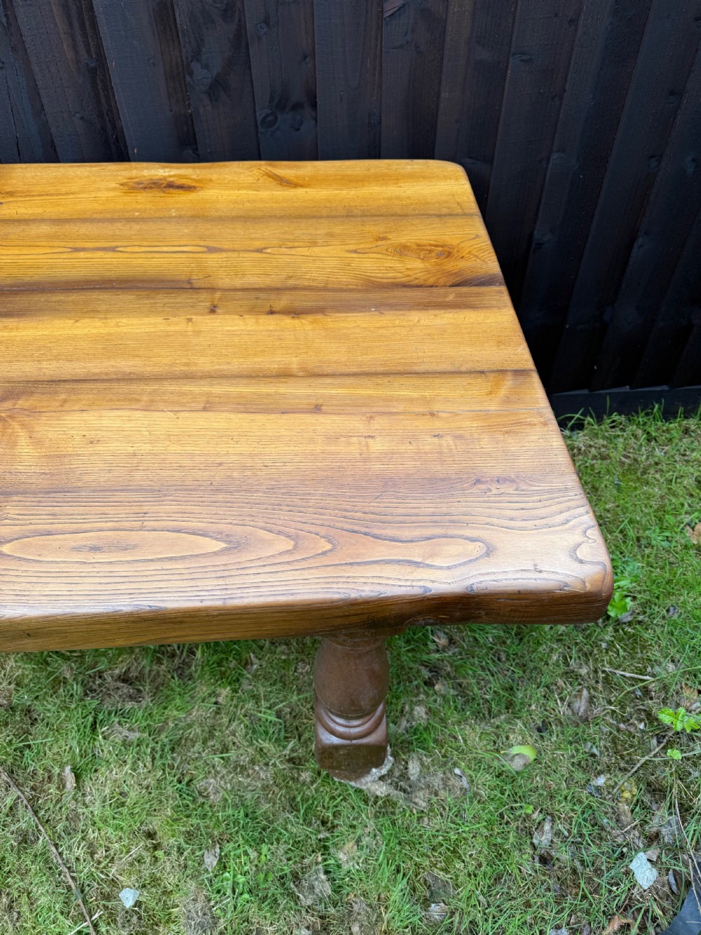 A large solid oak refectory dining table featuring a thick plank top, turned legs, and a low central stretcher base. View III