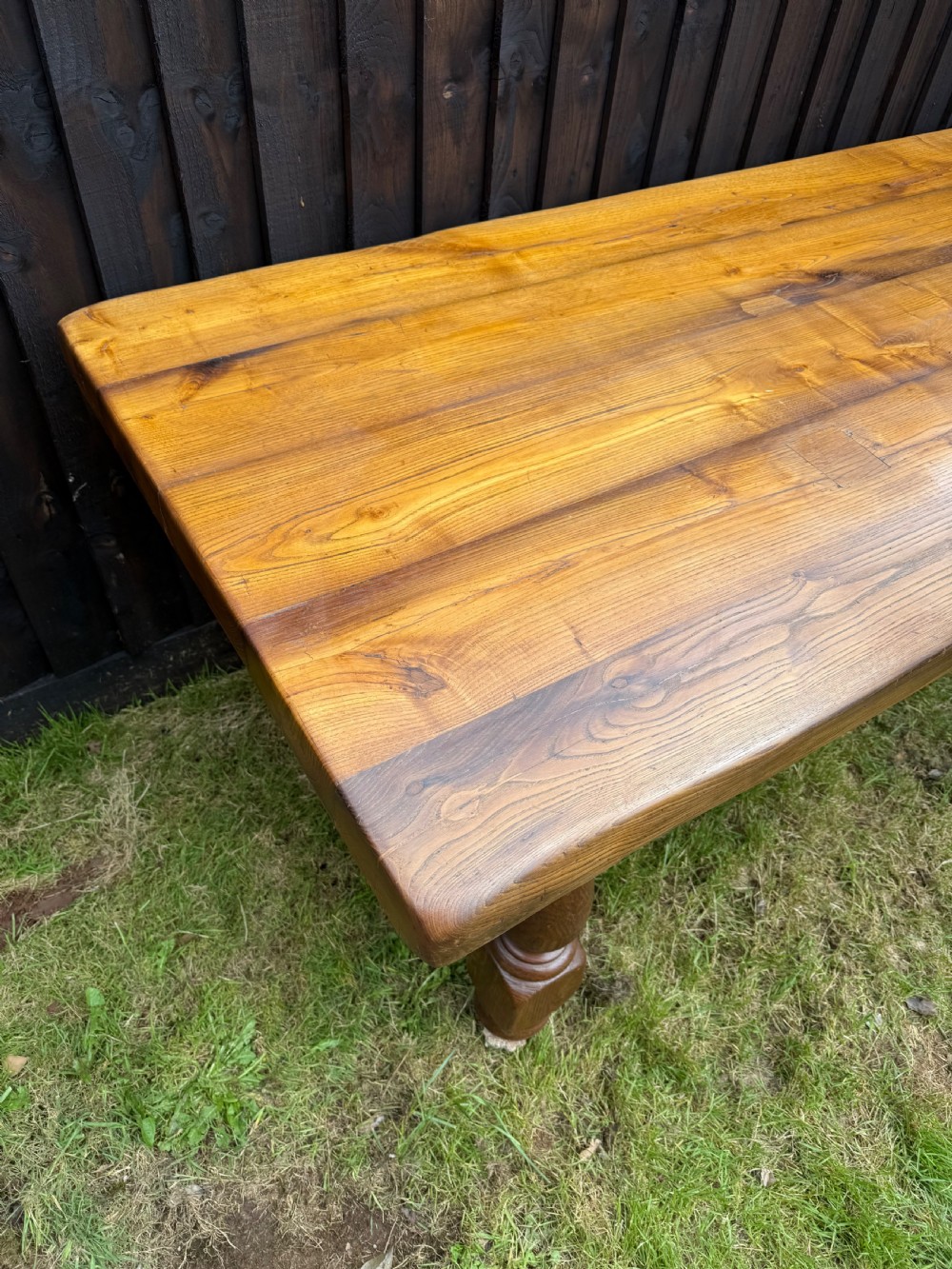 A large solid oak refectory dining table featuring a thick plank top, turned legs, and a low central stretcher base. View XI