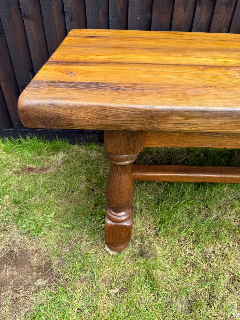 A large solid oak refectory dining table featuring a thick plank top, turned legs, and a low central stretcher base. View XIII