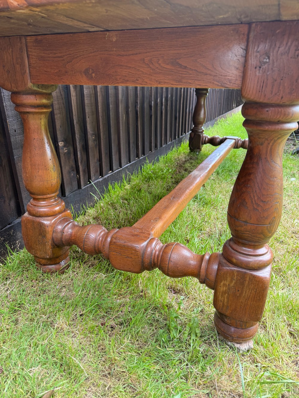 A large solid oak refectory dining table featuring a thick plank top, turned legs, and a low central stretcher base. View XX