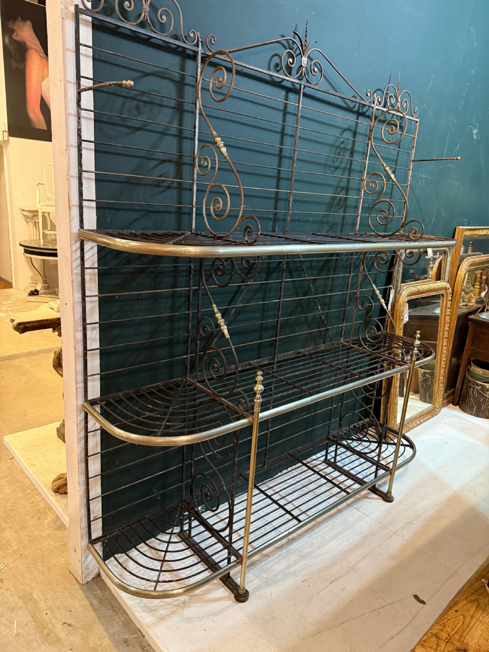 An antique French wrought iron and brass boulangerie rack featuring tier wire shelving and scrollwork cresting. View V