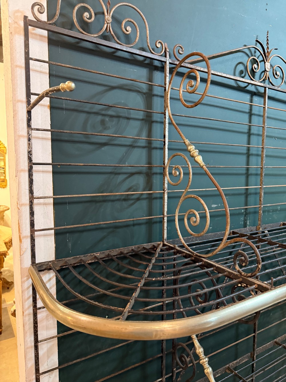 An antique French wrought iron and brass boulangerie rack featuring tier wire shelving and scrollwork cresting. View VI