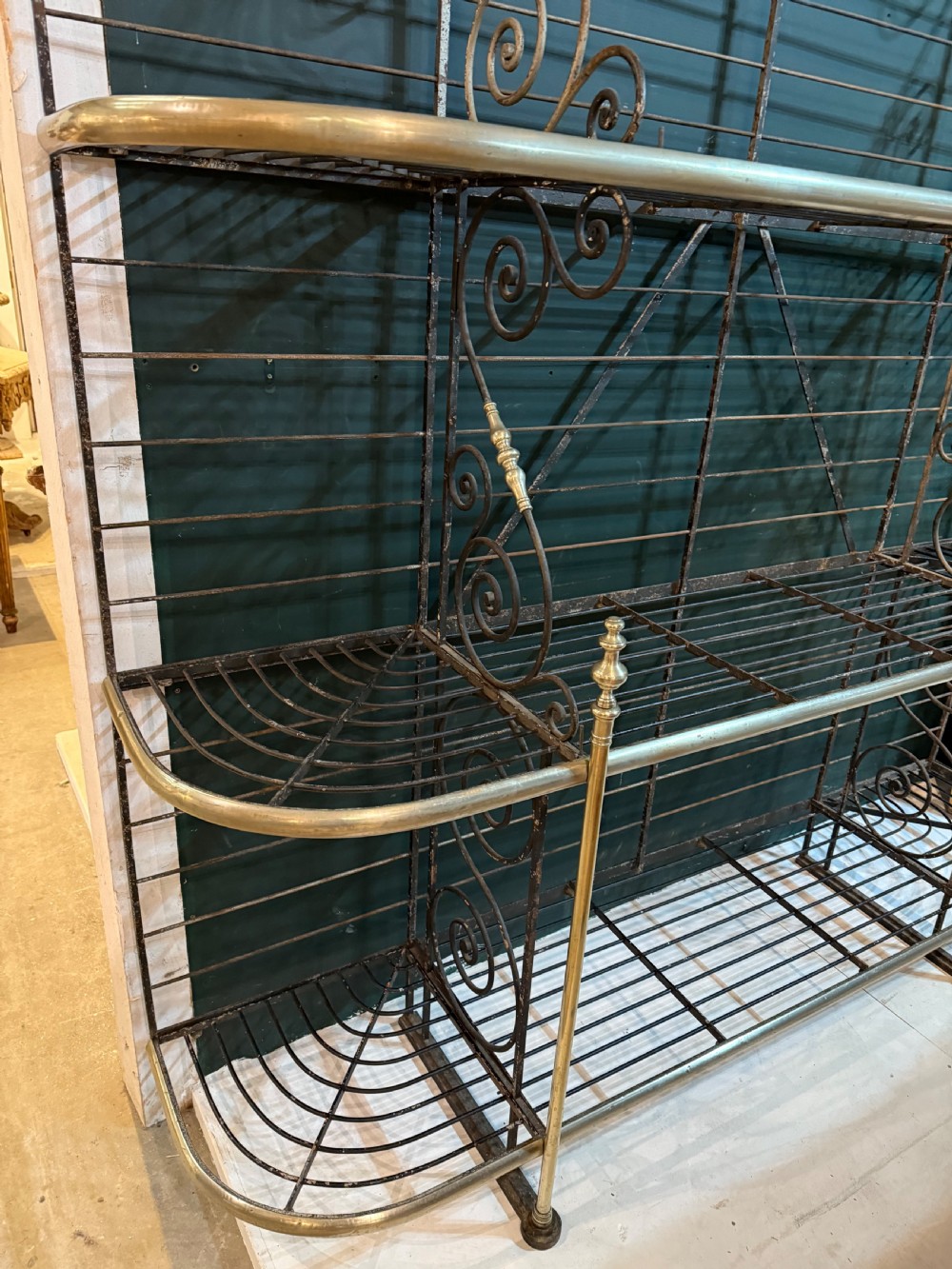 An antique French wrought iron and brass boulangerie rack featuring tier wire shelving and scrollwork cresting. View VII