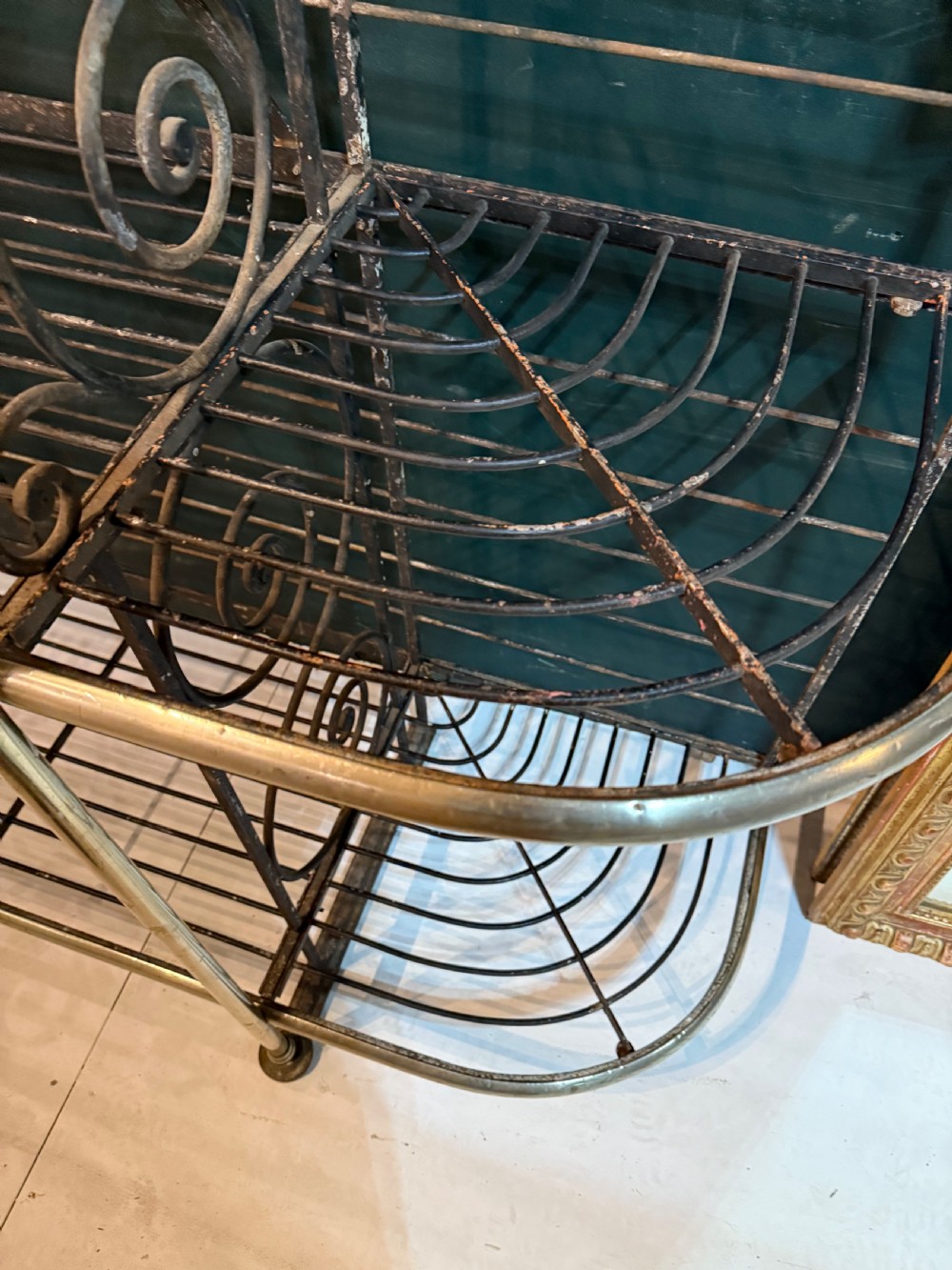An antique French wrought iron and brass boulangerie rack featuring tier wire shelving and scrollwork cresting. View X