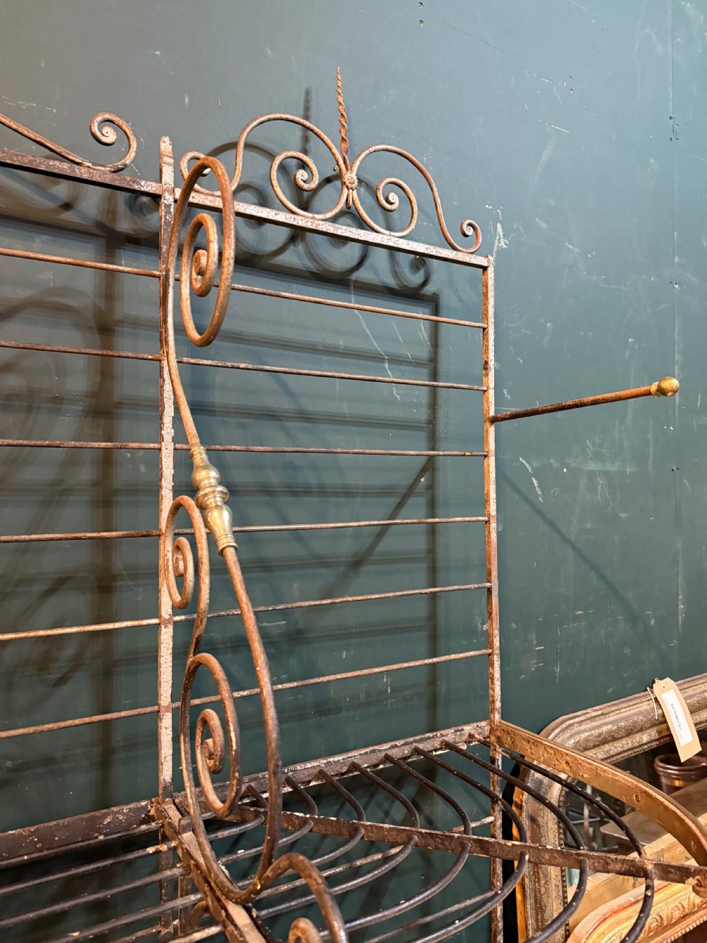 An antique French wrought iron and brass boulangerie rack featuring tier wire shelving and scrollwork cresting. View XII