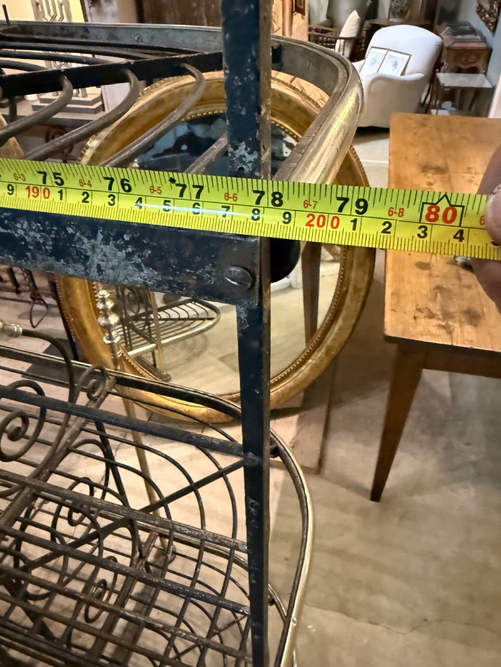 An antique French wrought iron and brass boulangerie rack featuring tier wire shelving and scrollwork cresting. View XV