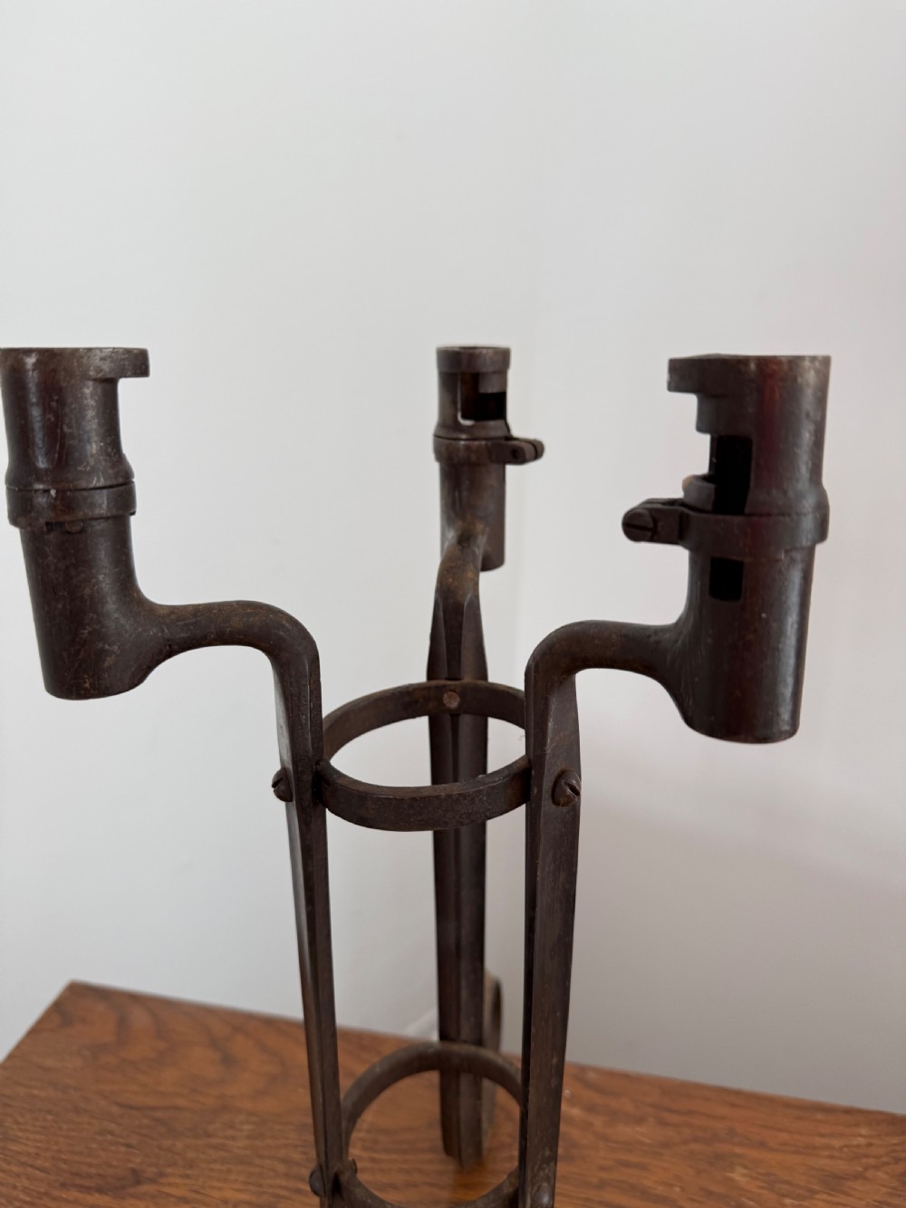 A pair of dark patinated metal three-light candelabras constructed from re-purposed military bayonet parts and scrollwork legs. View V