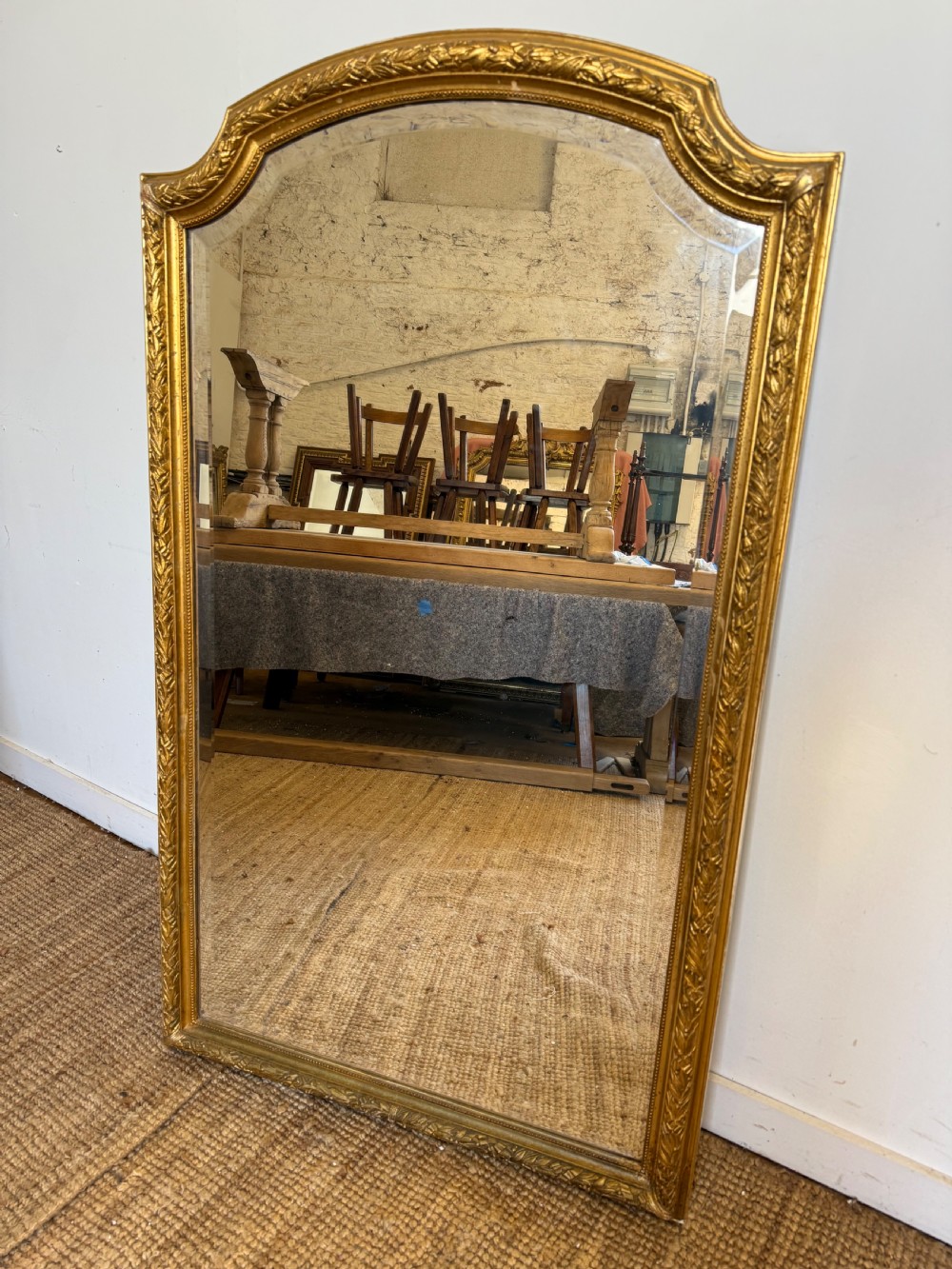 A late 19th-century tall arched-top wall mirror featuring a gilded wood frame with leaf moulding.