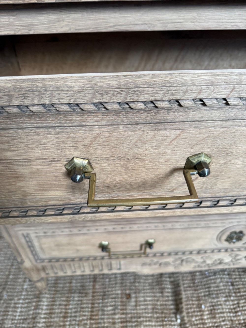 A rectangular scrubbed oak commode featuring three drawers with brass handles and subtle classical carved detailing on the facade. View VI