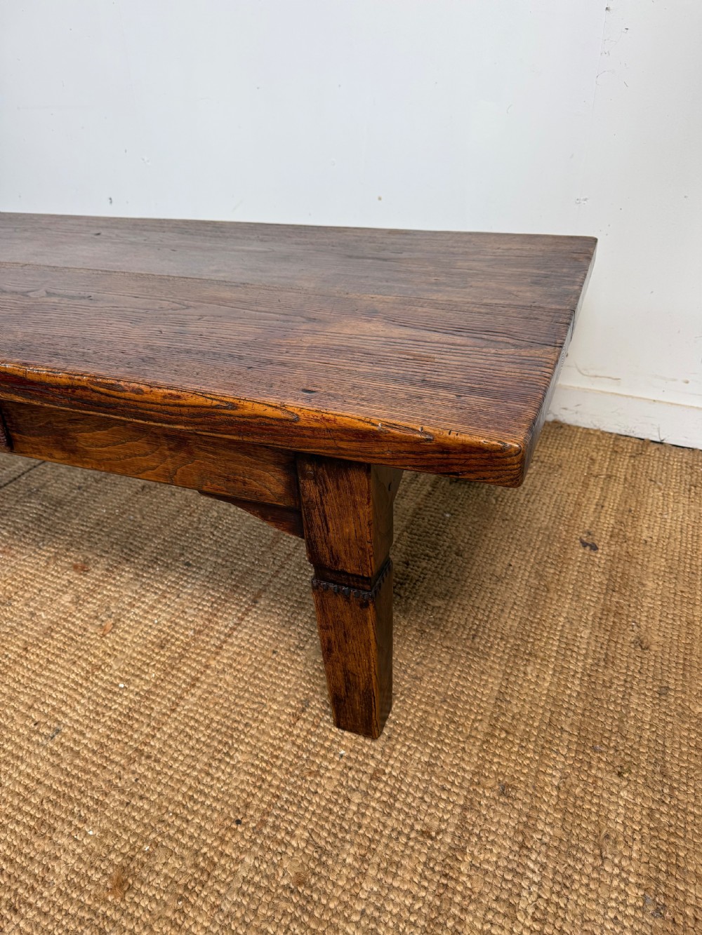 A low rectangular 19th-century dark elm coffee table featuring a wide plank top, central apron drawer with a round wooden knob, and four square legs. View II