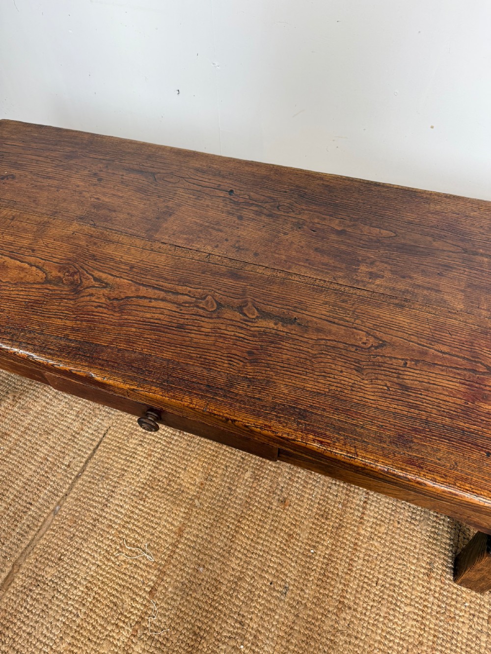 A low rectangular 19th-century dark elm coffee table featuring a wide plank top, central apron drawer with a round wooden knob, and four square legs. View VII