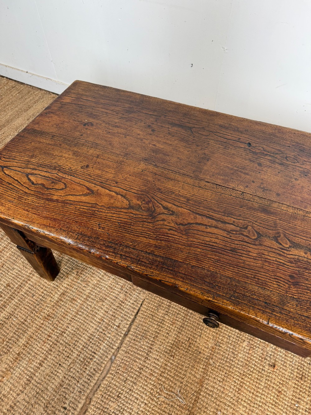 A low rectangular 19th-century dark elm coffee table featuring a wide plank top, central apron drawer with a round wooden knob, and four square legs. View VIII