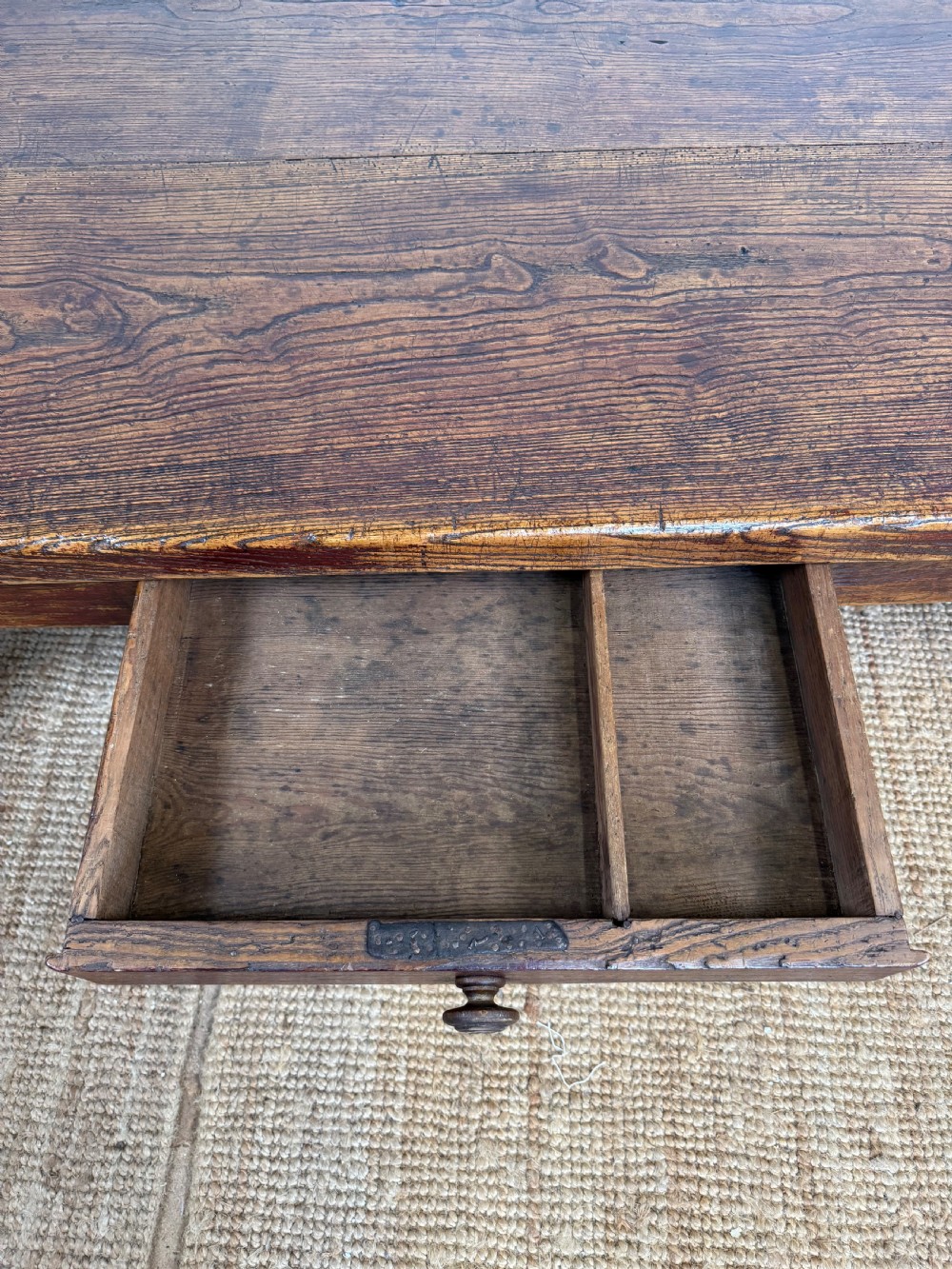A low rectangular 19th-century dark elm coffee table featuring a wide plank top, central apron drawer with a round wooden knob, and four square legs. View X