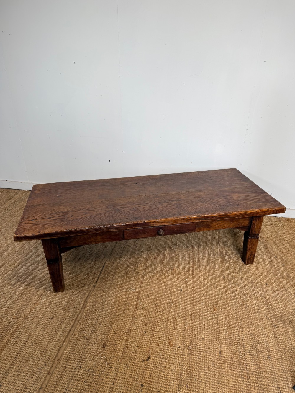 A low rectangular 19th-century dark elm coffee table featuring a wide plank top, central apron drawer with a round wooden knob, and four square legs. View XII