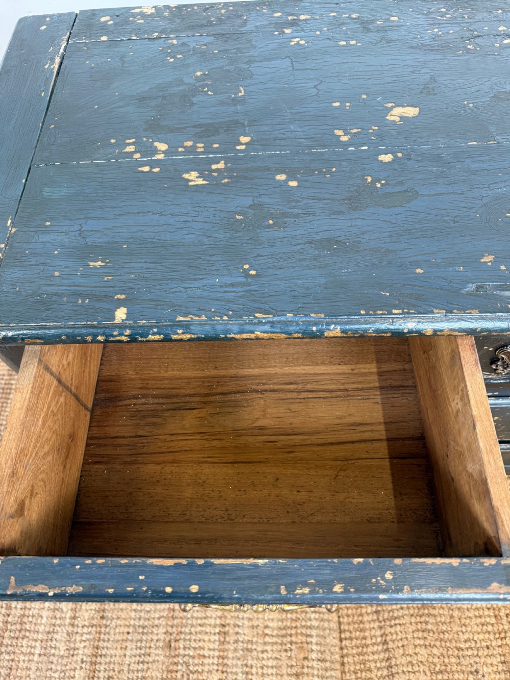 An antique dark-painted French commode featuring three rows of drawers with distressed black paint revealing bare wood underneath and decorative brass hardware. View VII