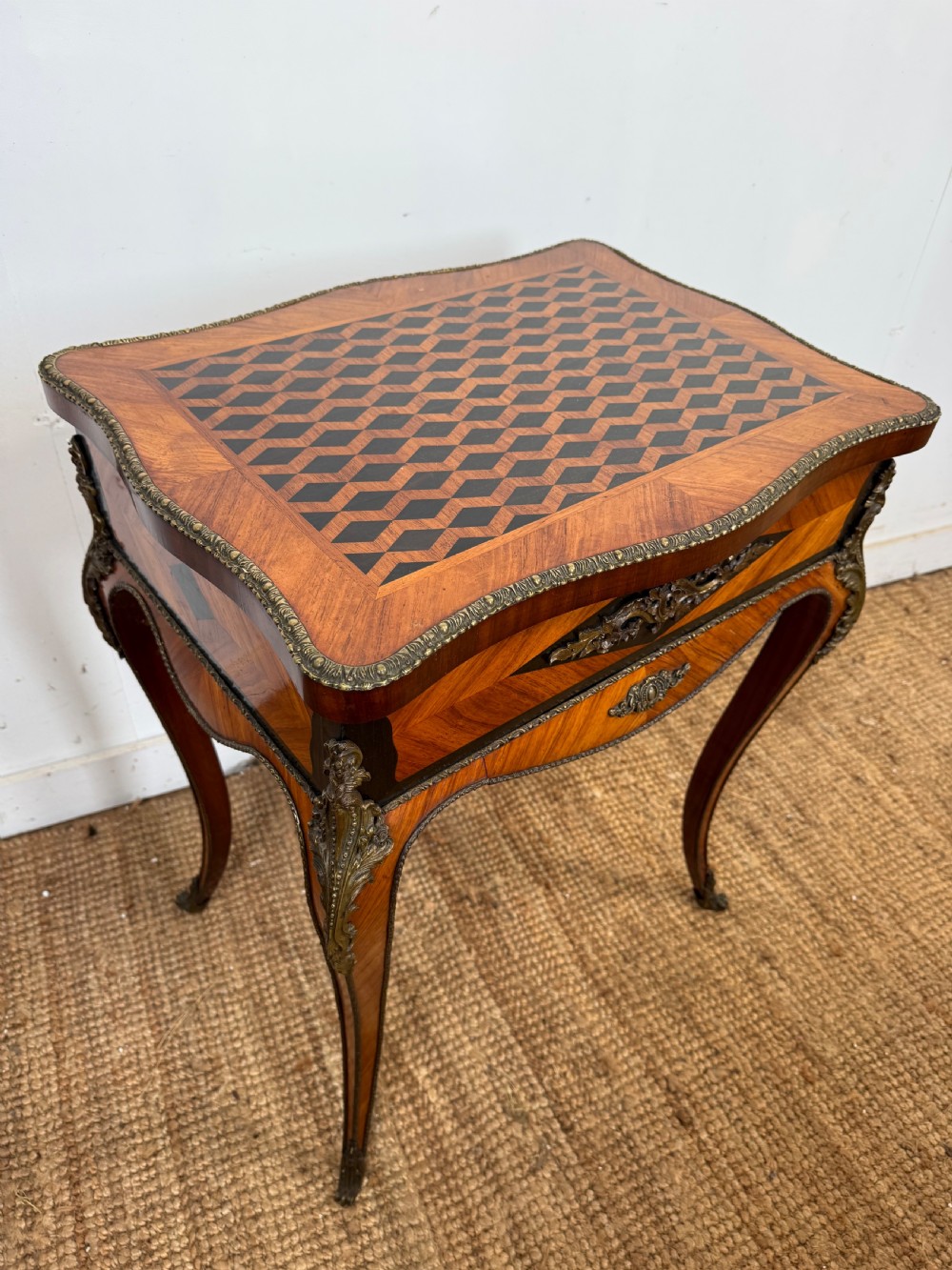 An antique French parquetry work table featuring a geometric optical illusion inlaid top, brass trim, and curved cabriole legs. View II