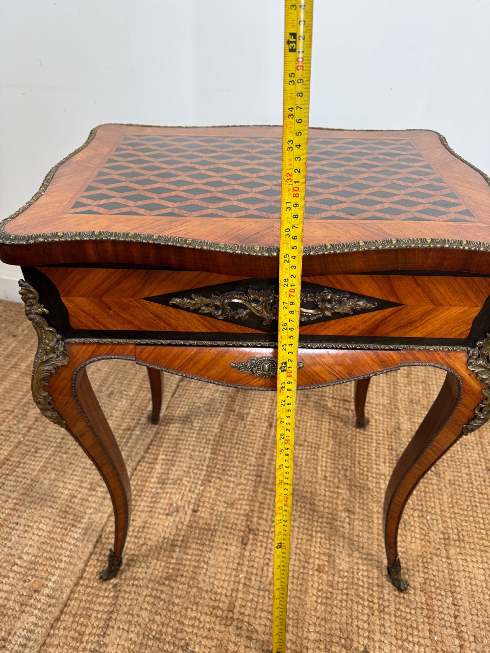 An antique French parquetry work table featuring a geometric optical illusion inlaid top, brass trim, and curved cabriole legs. View XIV