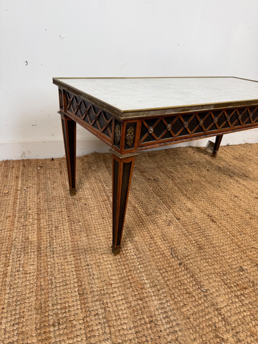 A rectangular Louis XVI style coffee table with a white marble top, dark wood lattice frieze, metal mounts, and tapered square legs. View II