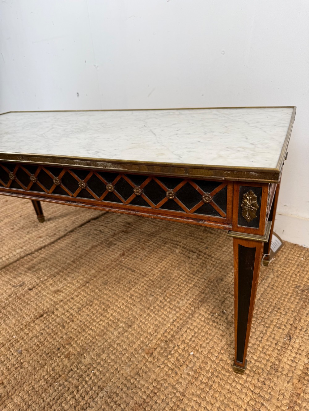 A rectangular Louis XVI style coffee table with a white marble top, dark wood lattice frieze, metal mounts, and tapered square legs. View V
