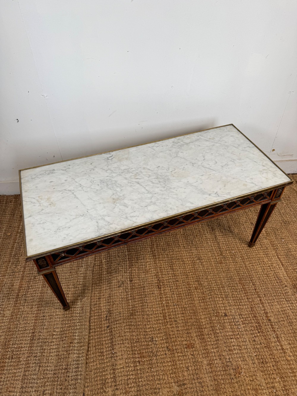 A rectangular Louis XVI style coffee table with a white marble top, dark wood lattice frieze, metal mounts, and tapered square legs. View VIII