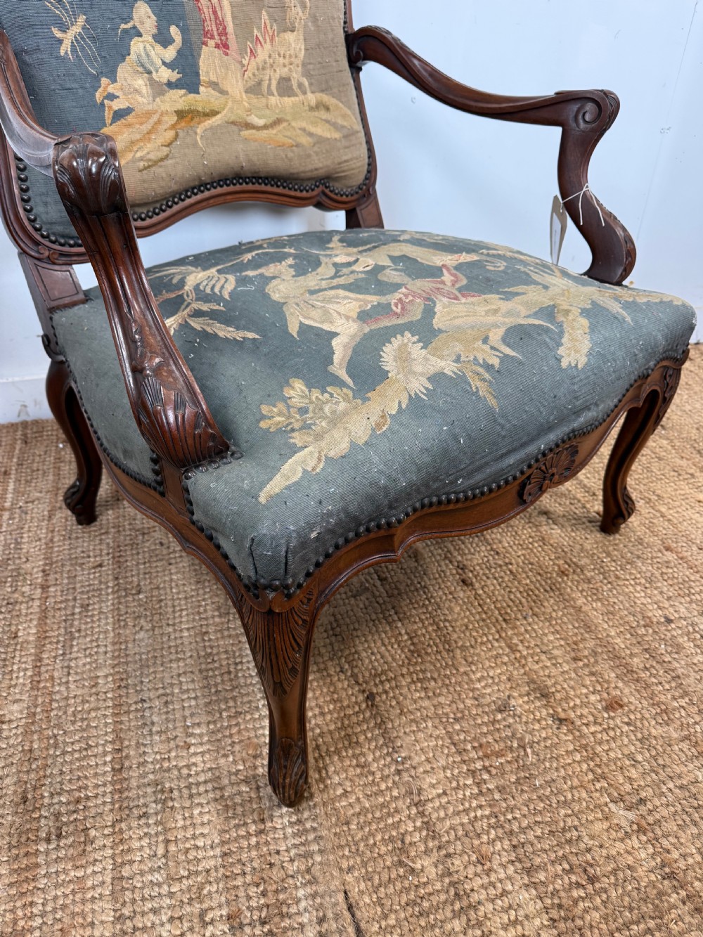 A late 19th-century open armchair with a carved walnut frame, cabriole legs, and muted green tapestry upholstery featuring pictorial motifs. View II