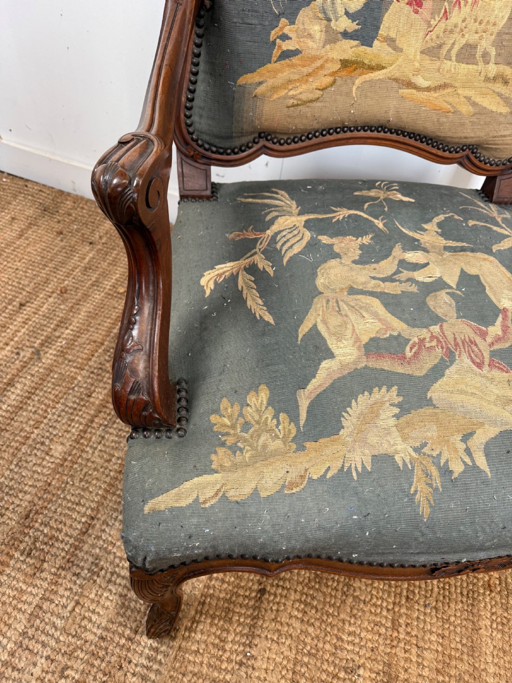 A late 19th-century open armchair with a carved walnut frame, cabriole legs, and muted green tapestry upholstery featuring pictorial motifs. View V