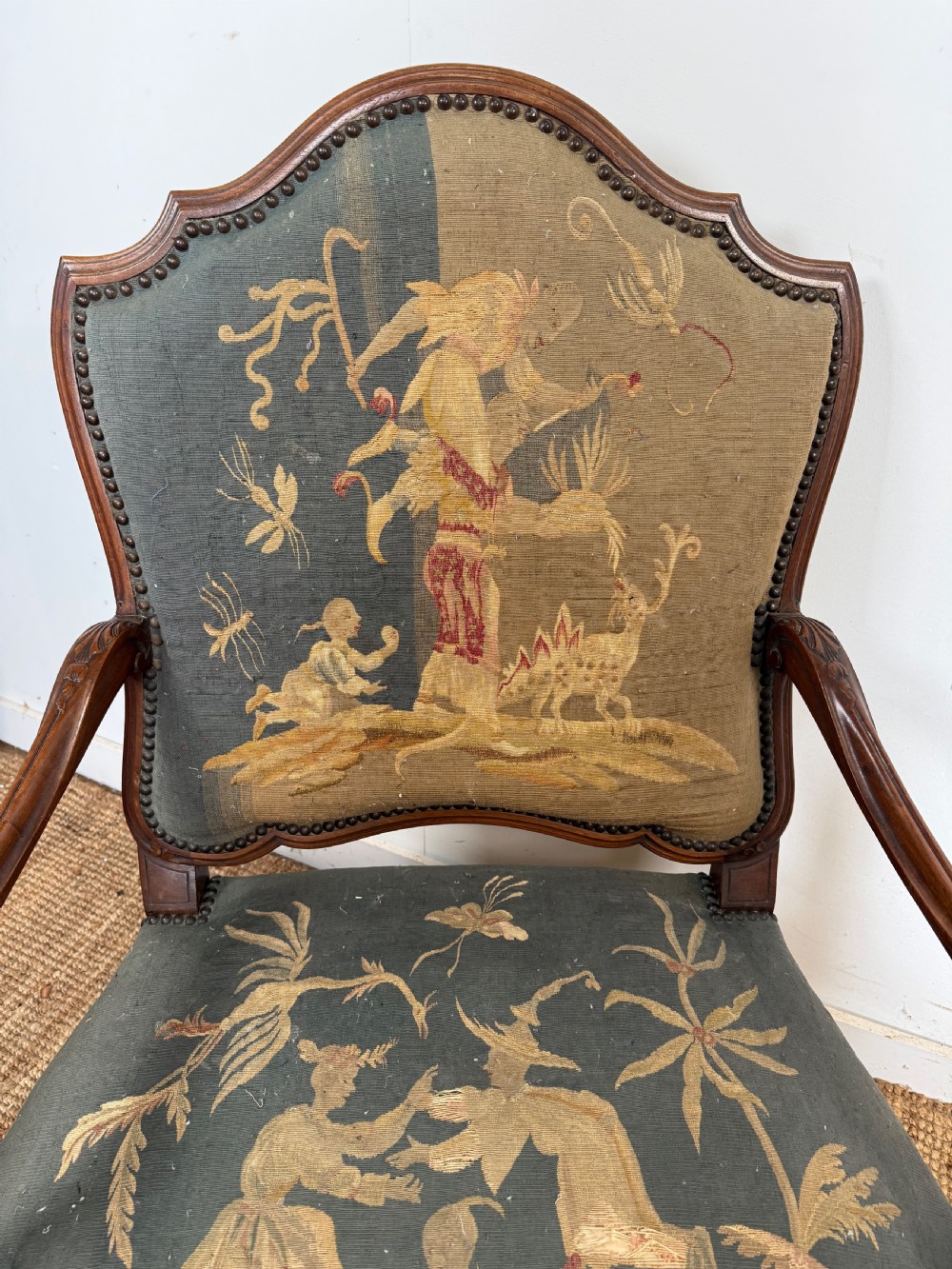 A late 19th-century open armchair with a carved walnut frame, cabriole legs, and muted green tapestry upholstery featuring pictorial motifs. View VI