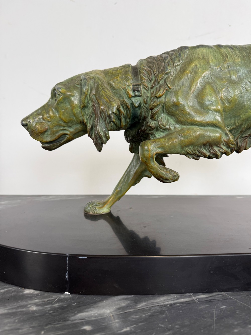 An Art Deco spelter sculpture depicting a prowling hunting dog with a green verdigris patina finish, mounted on an oval black marble base. View III