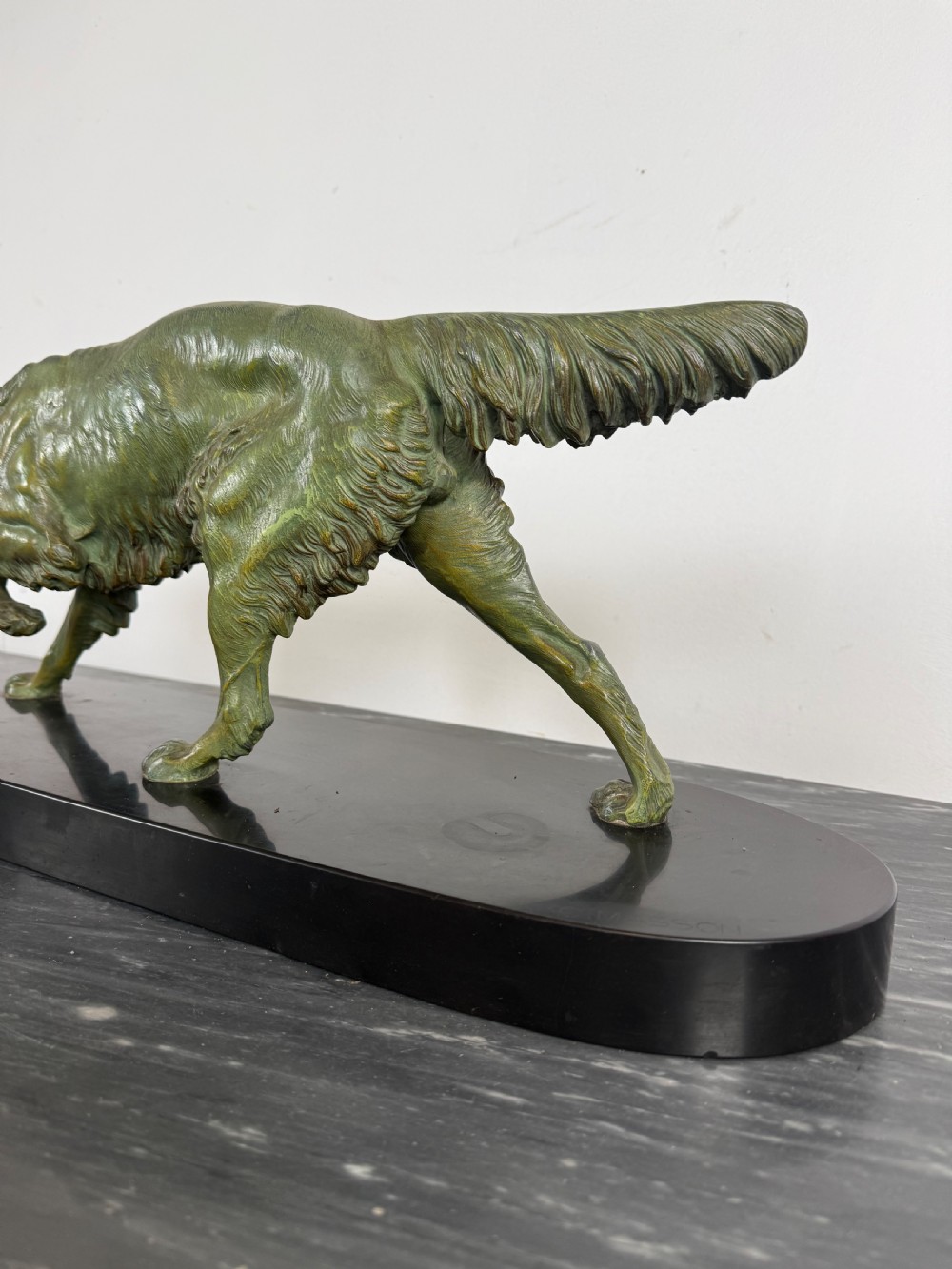An Art Deco spelter sculpture depicting a prowling hunting dog with a green verdigris patina finish, mounted on an oval black marble base. View IV