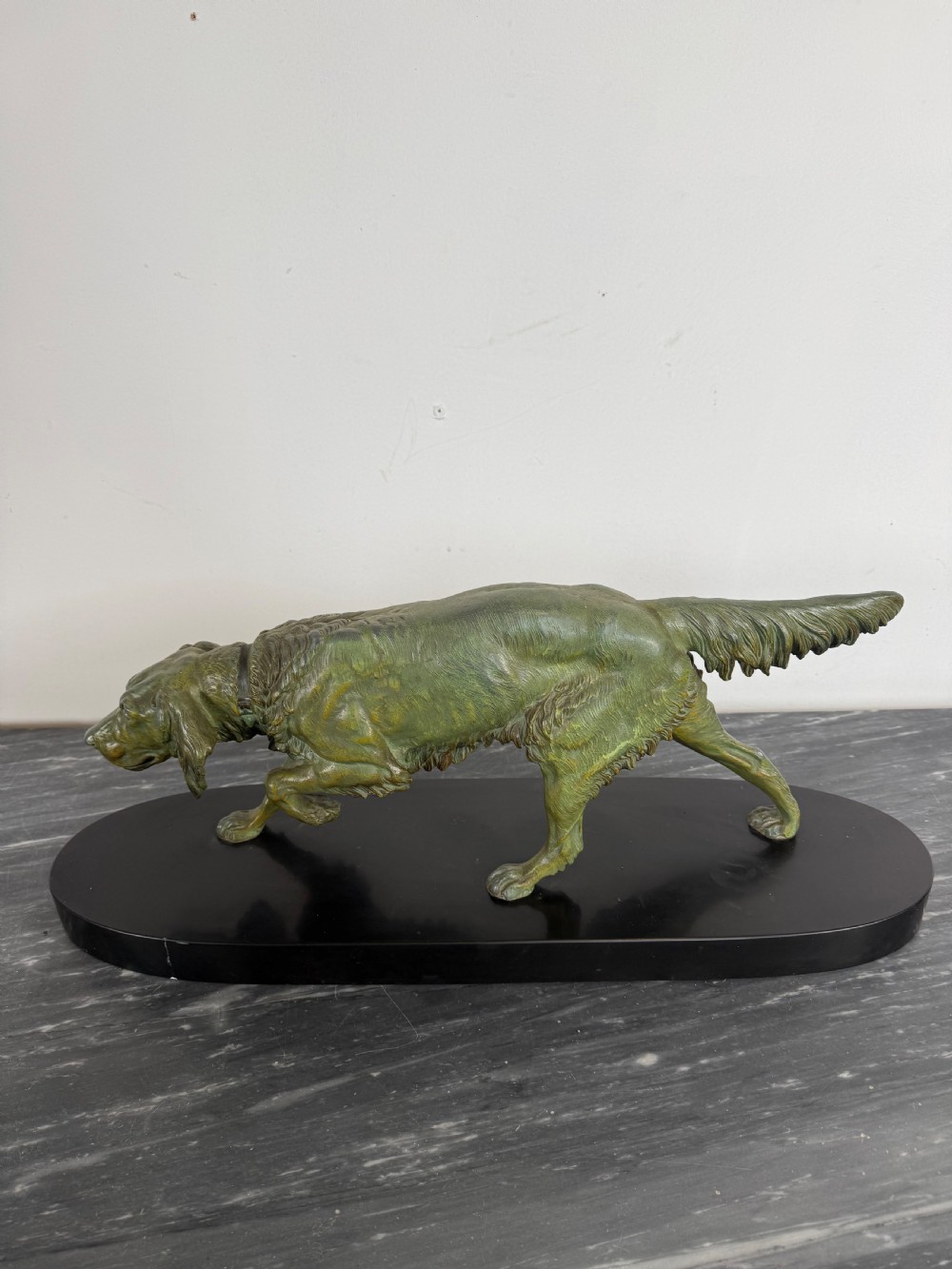 An Art Deco spelter sculpture depicting a prowling hunting dog with a green verdigris patina finish, mounted on an oval black marble base. View VII