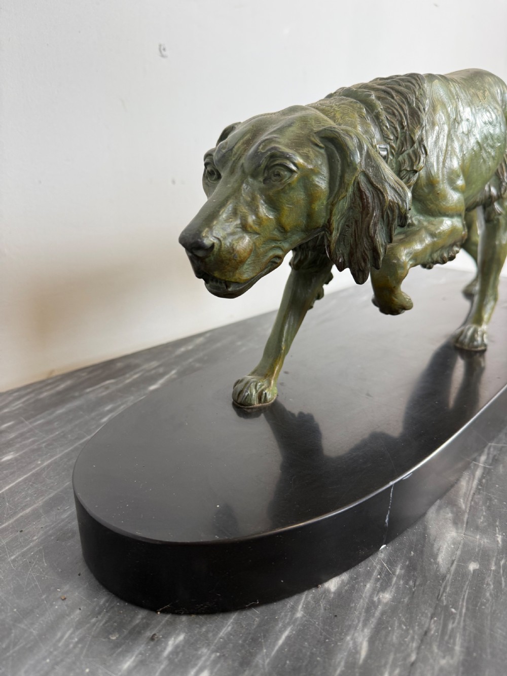 An Art Deco spelter sculpture depicting a prowling hunting dog with a green verdigris patina finish, mounted on an oval black marble base. View VIII