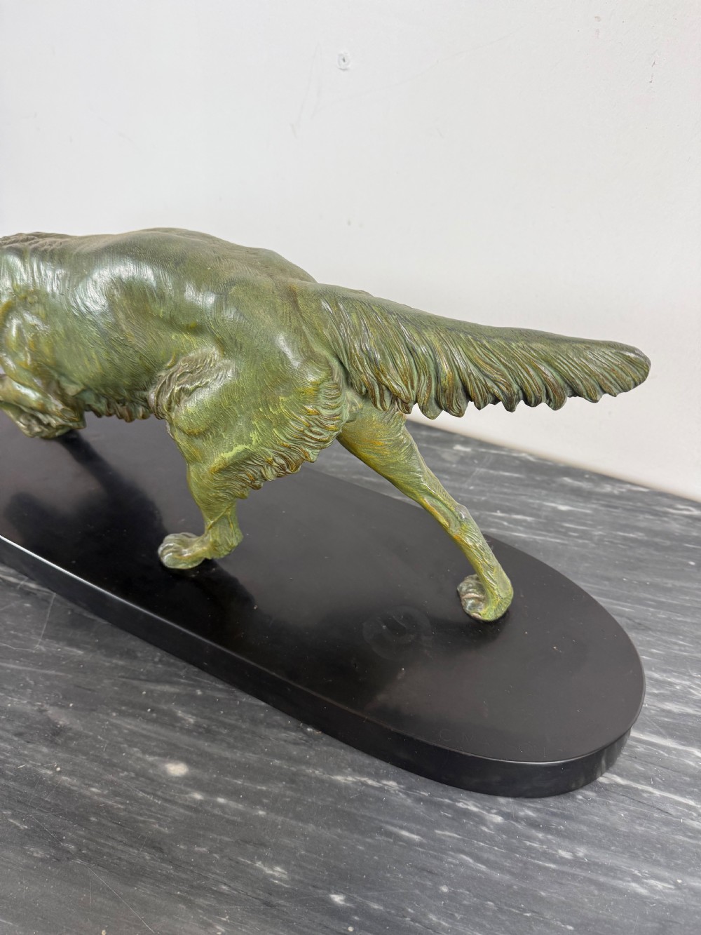 An Art Deco spelter sculpture depicting a prowling hunting dog with a green verdigris patina finish, mounted on an oval black marble base. View IX