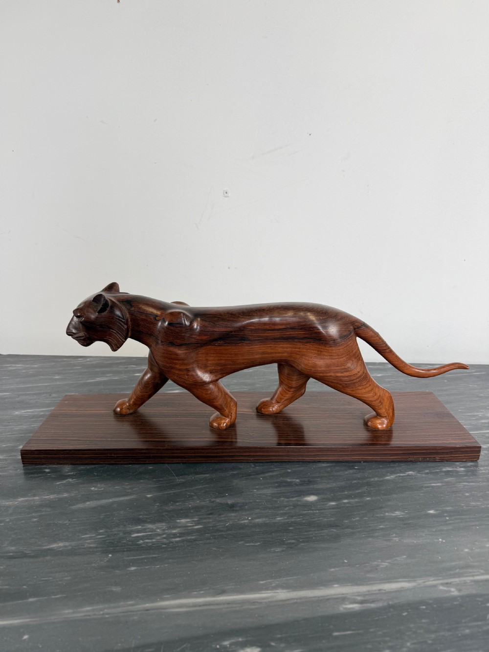 A carved dark wood Art Deco sculpture depicting a prowling panther mounted on a matching rectangular timber base.