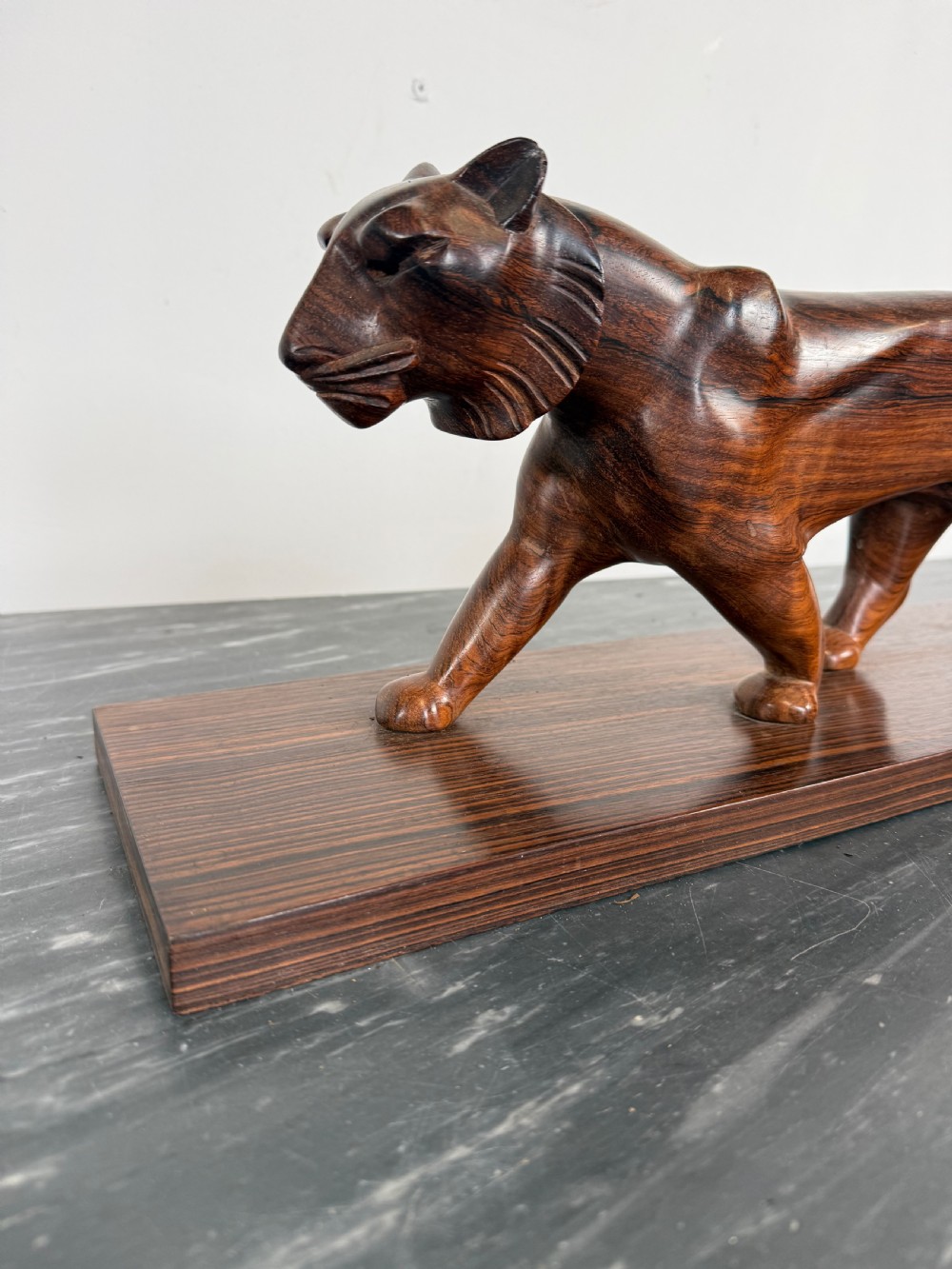A carved dark wood Art Deco sculpture depicting a prowling panther mounted on a matching rectangular timber base. View II