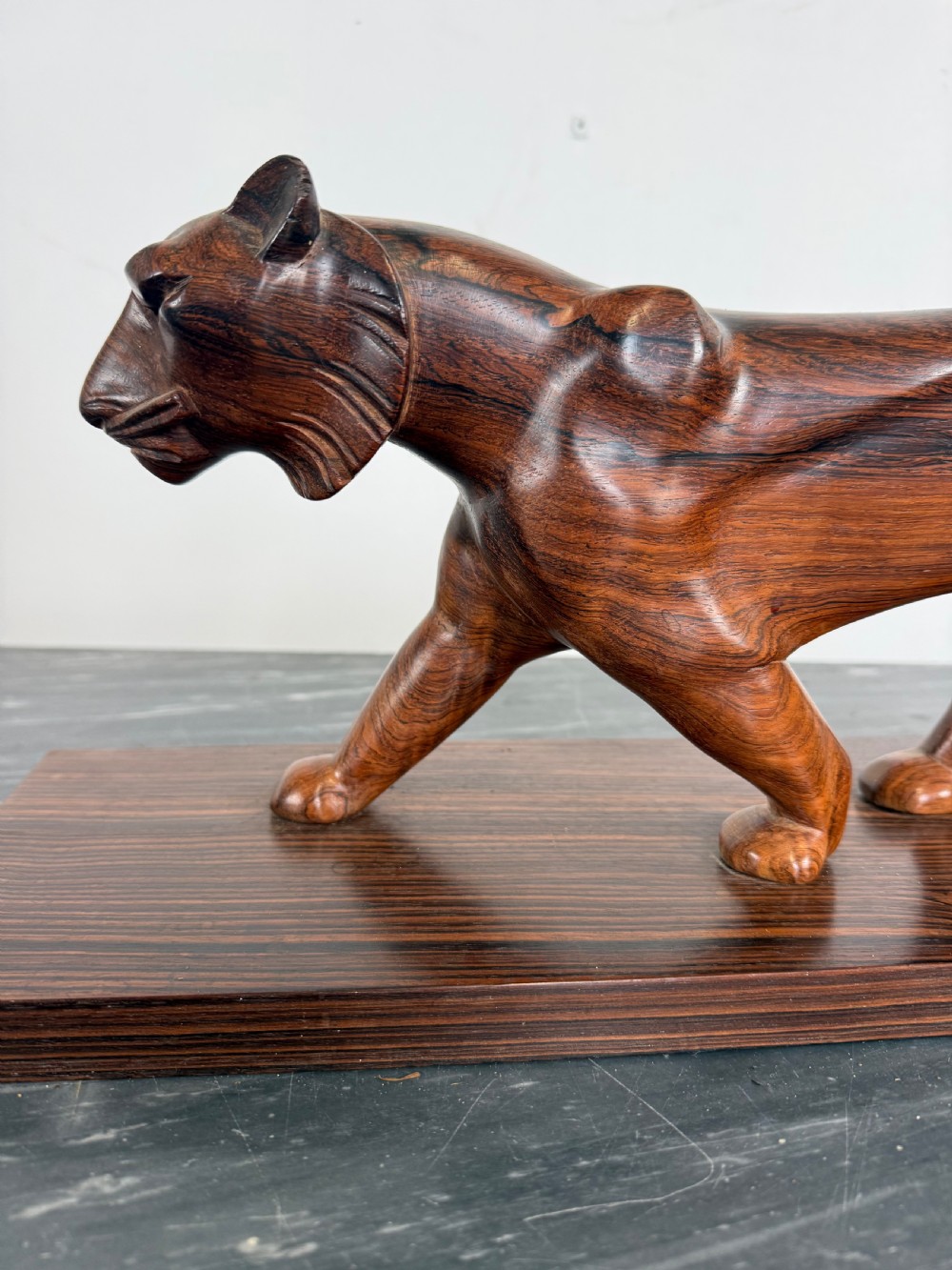 A carved dark wood Art Deco sculpture depicting a prowling panther mounted on a matching rectangular timber base. View III