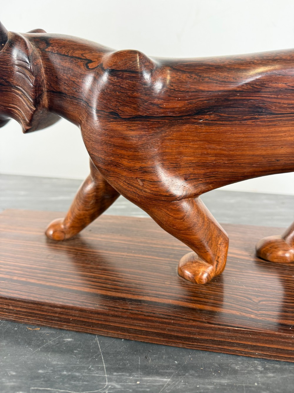 A carved dark wood Art Deco sculpture depicting a prowling panther mounted on a matching rectangular timber base. View VI