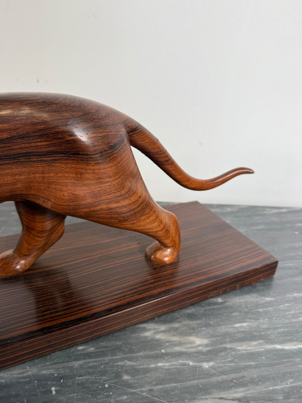A carved dark wood Art Deco sculpture depicting a prowling panther mounted on a matching rectangular timber base. View IX